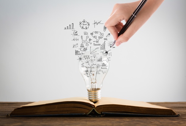 626x424 Person Drawing Symbols Coming Out Of A Light Bulb On Top Of A Book - Picture Of Person Drawing