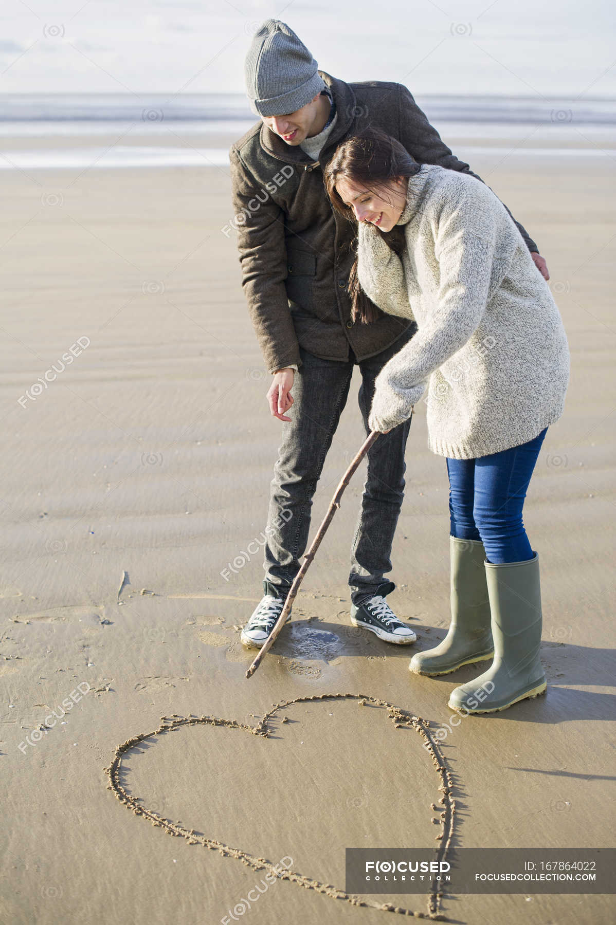 1198x1800 young couple drawing heart in sand, brean sands, somerset, england - Young Couple Drawing