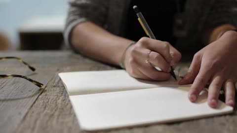 480x270 Someone Sketching In A Notebook While Their Glasses Rest On The - Sketching Someone